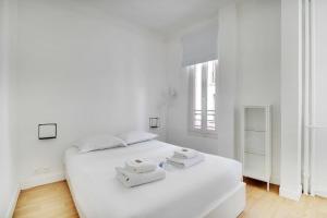 Un dormitorio blanco con una cama blanca con toallas. en Superb 2BR apartment - Suresnes en Suresnes