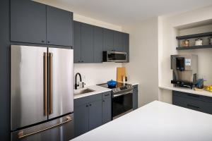a kitchen with black cabinets and a stainless steel refrigerator at The Neighborhood Hotel New Buffalo in New Buffalo