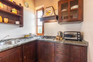 een keuken met houten kasten, een wastafel en een magnetron bij Borgo Dolci Colline Resort Limonaia in Castiglion Fiorentino