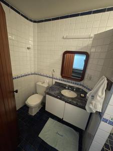 a bathroom with a toilet and a sink and a mirror at Guaeca Villa in São Sebastião