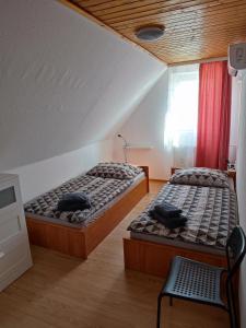 - une chambre avec deux lits et une chaise dans l'établissement Aranyharmat Apartman, à Balatonlelle