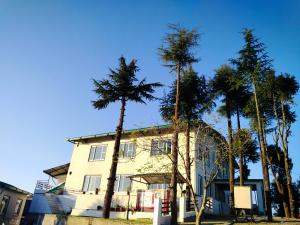 un edificio con palmeras delante en PinnacleHouse kanatal Uttarakhand, en Kanatal