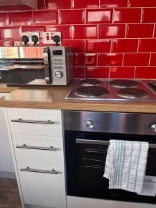 a kitchen with a stove and a red wall at Inviting Town House in Coventry