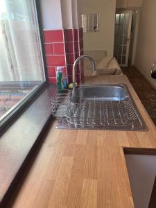 a kitchen sink with a dish rack on a counter at Inviting Town House in Coventry