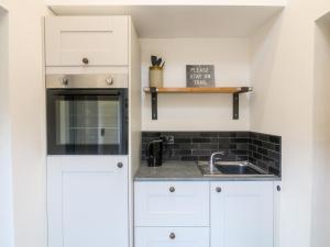 a kitchen with white cabinets and a sink at The Old Smokehouse in Rugeley