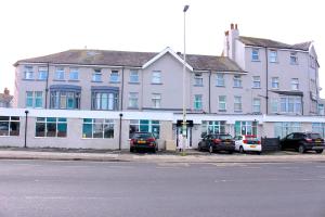 a large white building with cars parked in front of it at Henson Hotel Pleasure Beach in Blackpool