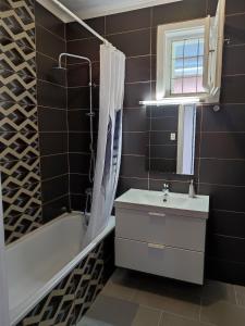 La salle de bains est pourvue d'un lavabo, d'une baignoire et d'un miroir. dans l'établissement Aranyharmat Apartman, à Balatonlelle