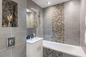 La salle de bains est pourvue d'une baignoire, d'un lavabo et d'une douche. dans l'établissement Modern flat in central golders green, à Londres