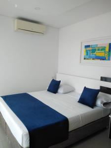 a large bed with blue pillows on top of it at Hotel Aguazul Plaza Centro in Aguazul