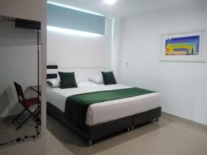 a bedroom with a bed with a green blanket at Hotel Aguazul Plaza Centro in Aguazul