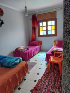 a room with two beds and a window at Gite Rahhaoui Simo in Kasba des Aït Moussa