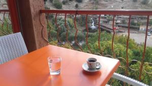 uma mesa laranja com uma chávena e um copo numa varanda em Gite Rahhaoui Simo em Kasba des Aït Moussa