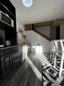 een keuken met zwarte kasten en houten vloeren bij Petite maison dans le beaujolais 