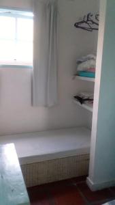 a white bathroom with a window and a bench at Antonia Hospedaria 1 in Búzios