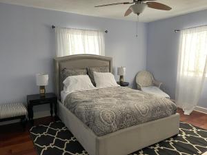 a bedroom with a bed and two windows and a fan at The Painted Lady, a spacious renovated 4BR Victorian in Saint Augustine