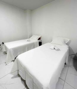 two beds in a room with white sheets at Apê 202 in Brasilia