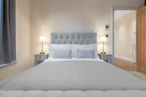 a bedroom with a large white bed with two lamps at Candler Mews in Twickenham