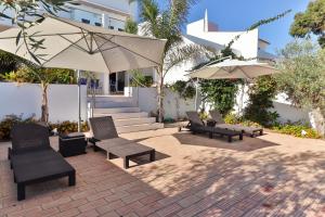 un patio avec des chaises et des parasols en face d'un bâtiment dans l'établissement Villa Fuseta 102 T, à Fuzeta