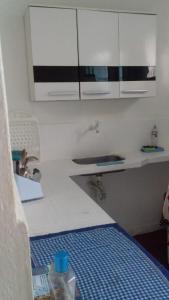 a kitchen with a bed and a sink and white cabinets at Antonia Hospedaria 1 in Búzios