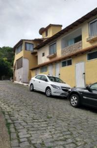 zwei Autos, die auf einer Kopfsteinpflasterstraße neben einem Gebäude geparkt sind in der Unterkunft Antonia Hospedaria 1 in Búzios