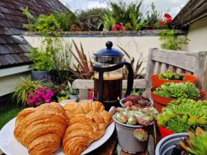 a table with a plate of croissants and a tea kettle at Carnethic Penthouse in Fowey