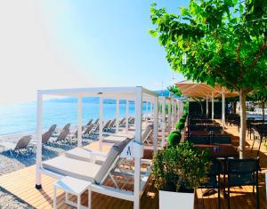 una spiaggia con sedie e ombrelloni e l'oceano di Akrata Beach Hotel a Akrata