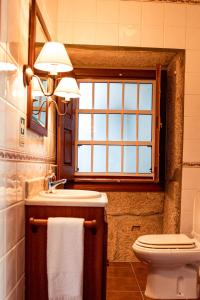 a bathroom with a sink and a toilet and a window at Casa Sobreira da Silva - Alojamento Local in Almeida
