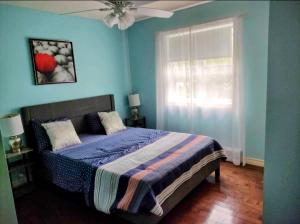 Dormitorio azul con cama y ventana en Chalet chez Divine!, en Trois-Rivières