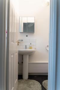 4 bedroom home - free parking by Ideel Apartments in Milton Keynes في Wolverton: حمام مع حوض ومرآة