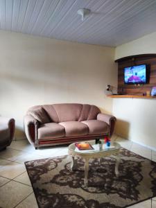 uma sala de estar com um sofá castanho e uma mesa de centro em Casa Verde em Joinville