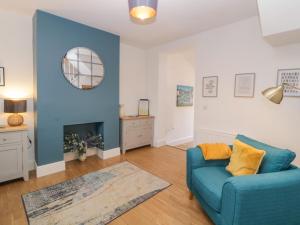 a living room with a blue couch and a fireplace at Keeling in Exmouth
