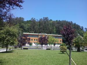 a building in a park with trees in front of it at Albergue El Floran in Blimea