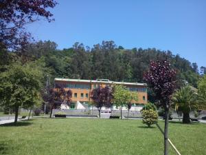 ein Gebäude in einem Park mit Bäumen davor in der Unterkunft Albergue El Floran in Blimea