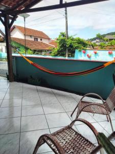 a hammock on a porch with two chairs at Casa Verde in Joinville