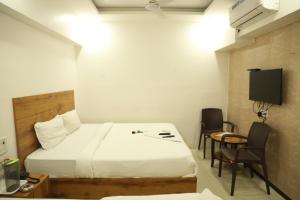 a hotel room with a bed and a table and chairs at Hotel Shiv Leela Grand in Mumbai