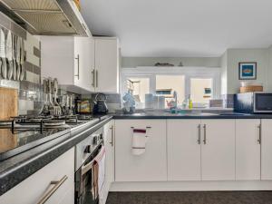 a white kitchen with white cabinets and appliances at Pass the Keys Little Haven A stunning Bungalow in Minnis Bay in Birchington