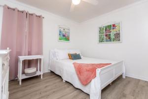 um quarto branco com uma cama branca e 2 janelas em Cypress Landing em Pass Christian