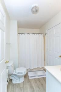 a white bathroom with a toilet and a shower at Cypress Landing in Pass Christian