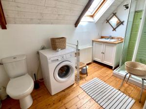 uma casa de banho com uma máquina de lavar roupa e um WC em LA MAISON BLEUE,authenticité, nature, simplicité, 2-5 personnes, Moëlan sur Mer em Moëlan-sur-Mer