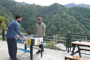 two men playing a game on a table in the mountains at Griffons Cafe and Stay in Dharamshala