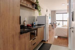 a kitchen with wooden cabinets and a refrigerator at Studio encantador em Poços de Caldas-MG PGO209 in Poços de Caldas