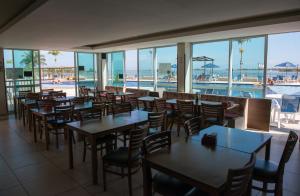 ein Restaurant mit Tischen und Stühlen und einem Pool in der Unterkunft Arraial do Cabo - Apartamento no paraíso! in Arraial do Cabo