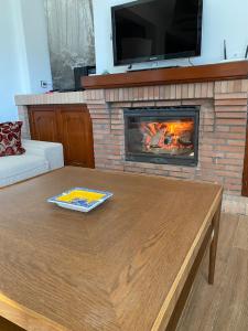 a living room with a fireplace and a wooden coffee table at Casa de campo "La Campanera" in Constantina