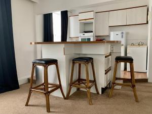 una cocina con 2 taburetes y una barra en Sarum Apart-Hotel en Saint Helier