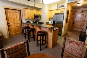 una cocina con armarios de madera y taburetes de bar en Silverado Lodge - 1 Bedroom Suite with King Bed & Pool View apartment hotel en Park City