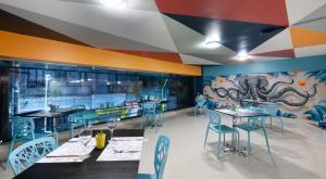 um restaurante com mesas e cadeiras e um mural em Mural Living Hotel Manaus em Manaus
