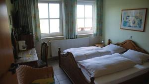 a bedroom with two beds and a table and two windows at Ferienhof Rustemeier in Altenberge