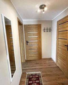 a hallway with two wooden doors and a rug at Apartament Nadwodnia 37 in Łapsze Niżne