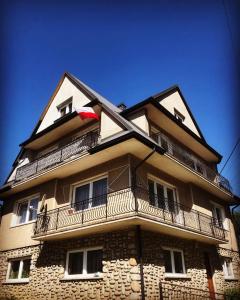 a tall building with a balcony on top of it at Apartament Nadwodnia 37 in Łapsze Niżne