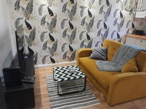 salon z żółtą kanapą i tapetą w obiekcie Apartament "Konie i anioły" w mieście Boguszów-Gorce